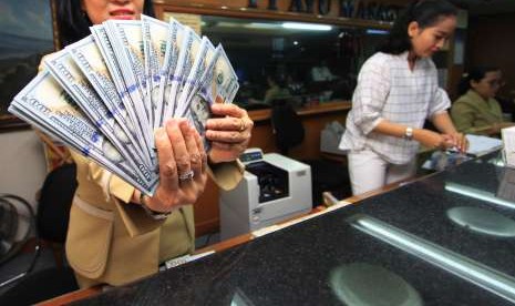 Karyawan menghitung mata uang Dollar AS di gerai jasa penukaran uang asing di Jakarta, Senin (13/8). 