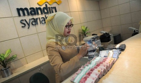  Karyawan menghitung uang di bangking hall Bank Syariah Mandiri, Jakarta, Selasa (17/11). 