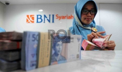  Karyawan menghitung uang di Banking Hall Bank BNI Syariah, Jakarta, Rabu (2/12).