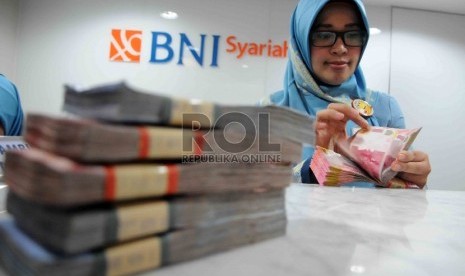 Karyawan menghitung uang di Banking Hall Bank BNI Syariah, Jakarta, Rabu (2/12). 