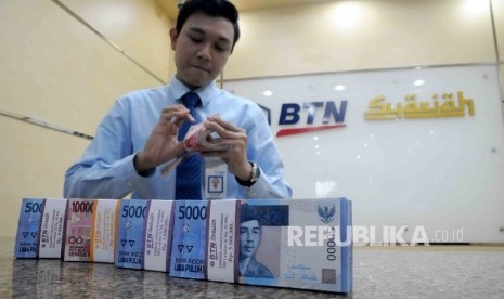 Karyawan menghitung uang di banking hall Bank BTN Syariah, Jakarta, Kamis (21/1).