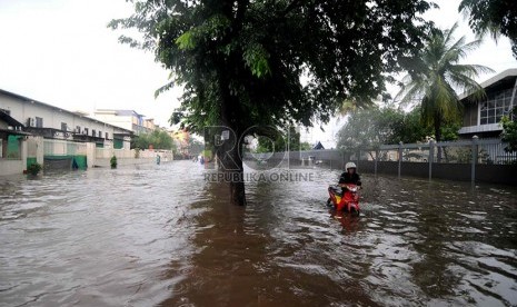   Seorang karyawan mendorong sepeda motornya melewati banjir yang menggenangi Kawasan Industri Pulo Gadung, Jakarta Timur, Rabu (5/2).    (Republika/ Wihdan)