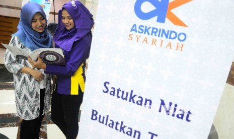 Karyawati berbincang didekat banner Askrindo Syariah di Kantor Jaminan Pembiayaan Askrindo Syariah, Jakarta, Senin (3/10).