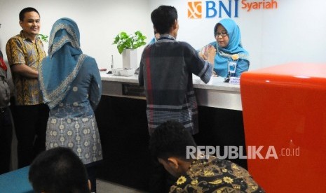  Karyawati melayani nasabah di banking hall Bank BNI Syariah, Jakarta, Jumat (10/2).