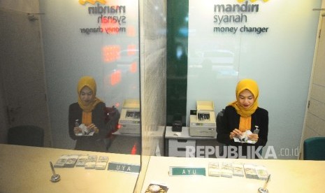  Karyawati menghitung dolar AS di Banking Hall Bank Syariah Mandiri, Jakarta, Selasa (18/4).