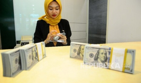  Karyawati menghitung dolar AS di Banking Hall Bank Syariah Mandiri, Jakarta, Selasa (18/4). 