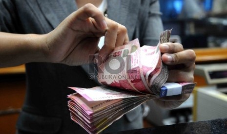  Karyawati menghitung mata uang rupiah di salah satu tempat penukaran valuta asing di Jakarta, Selasa (15/12). 