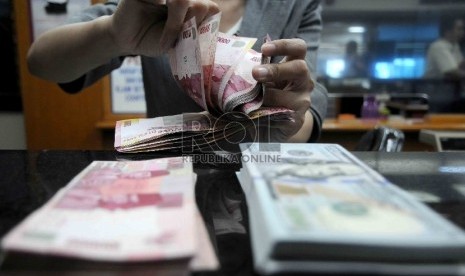  Karyawati menghitung mata uang rupiah di salah satu tempat penukaran valuta asing di Jakarta, Selasa (15/12).