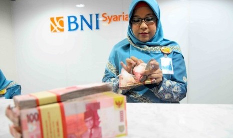 Karyawati menghitung uang di banking Hall bank BNI Syariah, Jakarta. ilustrasi