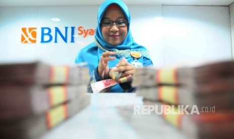 Karyawati menghitung uang di banking Hall bank BNI Syariah, Jakarta. ilustrasi