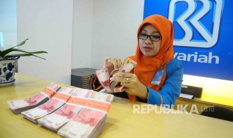  Karyawati menghitung uang di Banking Hall Bank BRI Syariah, Jakarta.