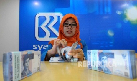 Karyawati menghitung uang di Banking Hall Bank BRI Syariah, Jakarta, Kamis (11/8). (Republika/Agung Supriyanto)