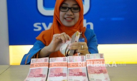 Karyawati menghitung uang di Banking Hall Bank BRI Syariah, Jakarta, Selasa (29/11).