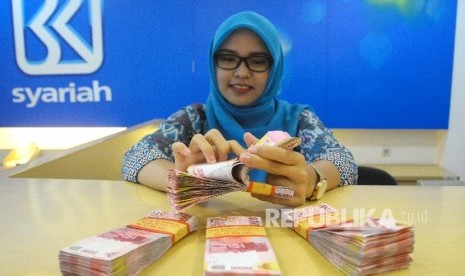 Karyawati menghitung uang di Banking Hall Bank BRI Syariah, Jakarta, Selasa (7/3).