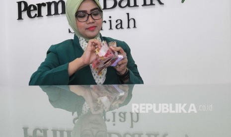 Karyawati menghitung uang di Banking hall Bank Permata Syariah, Jakarta, Selasa (14/3).