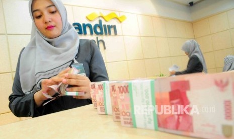  A teller was counting money at Banking Hall Bank Syariah Mandiri, Jakarta. The assets of sharia banks rose 18.49 percent y-o-y to Rp305.5 trillion by July, 2016 on growing third party funds.