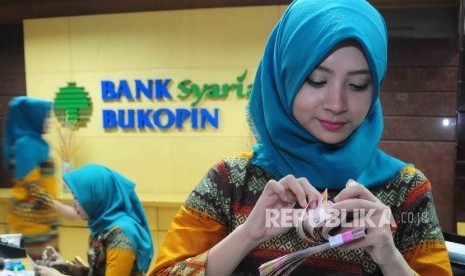 Karyawati menghitung uang di banking hall Bank Syariah Bukopin (BSB).  (Republika/ Agung Supriyanto)