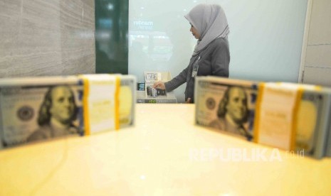 Karyawati menghitung uang dolar AS di tempat penukaran uang Bank Mandiri Syariah, Jakarta, Kamis (20/10). 