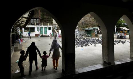 Kashmiri Muslim children run playfully towards a group of pigeons in the compound of a shrine in Srinagar, India.