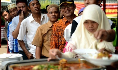  Kaum dhuafa mengantre mengambil makan saat mengikuti makan siang bersama dalam acara dapur peduli Idhul Adha 2013 di pelataran masjid Al-Azhar, Jakarta, Rabu (16/10).   (Republika/Agung Supriyanto)