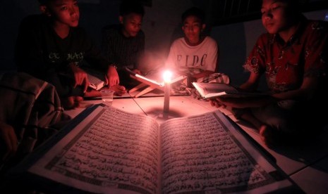 Kaum musllim membaca Alquran dengan penerangan lilin saat listrik padam di Desa Meunasah Alue, Muara Dua, Lhokseumawe, Aceh, Jumat (9/6) dini hari. 