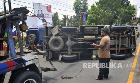 Petugas derek berupaya mengevakuasi truk yang terguling. (Ilustrasi)