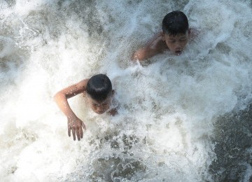 Keceriaan para bocah ketika bermain air terlihat di saluran irigasi di kawasan Neglasari, Tangerang, Banten, Rabu (14/9). Bermain air menjadi cara mereka untuk mengusir panasnya selama kemarau. (Republika/Aditya)