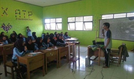 Kegiatan belajar-mengajar di SMK Teluk Kepayang (foto atas), Defti, berkerudung hitam (foto bawah).