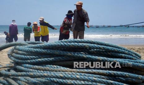 Kelompok buruh nelayan menarik jaring tarik yang ditebar di sekitar perairan Pantai Sine, Tulungagung, Jawa Timur, Selasa (19/10/2021). Buruh nelayan mendapatkan upah sebesar Rp20 ribu untuk sekali tarik jala. 