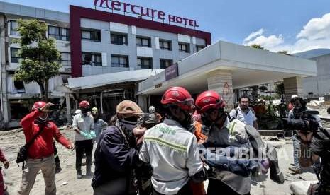 Keluarga korban dibawa petugas usai menyaksikan jenazah keluarganya yang menjadi korban gempa tsunami Palu di Hotel Mercure, Palu, Sulawesi Tengah, Jumat (5/10). 