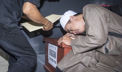 Keluarga korban menangis disamping peti berisi jenazah korban kebakaran pabrik kembang api seusai diserahterimakan di Posko Post Mortem di RS Polri Sukanto, Kramat Jati, Jakarta, Minggu (29/10). 