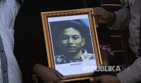 Keluarga korban penembakan kelompok kriminal bersenjata (KKB) memegang foto Muhammad Agus saat jenazah tiba di Landasan Udara Hasanuddin, Kabupaten Maros, Sulawesi Selatan, Jumat (7/12)