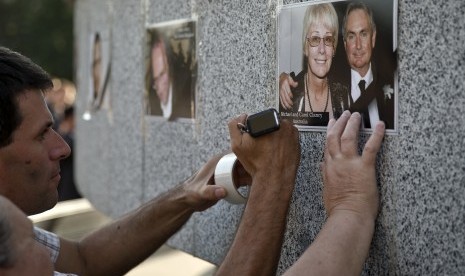 Keluarga korban pesawat Malaysia Airlines MH17 yang jatuh menempel foto kerabat mereka di dinding memorial di Kharkiv, Ukraina, Kamis (24/7).