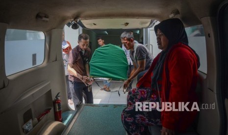 Keluarga membawa jenazah korban meninggal akibat keracunan minuman keras (miras) oplosan ke dalam mobil ambulans di Rumah Sakit Umum Daerah (RSUD) Cicalengka, Kabupaten Bandung, Jawa Barat, Senin (9/4).