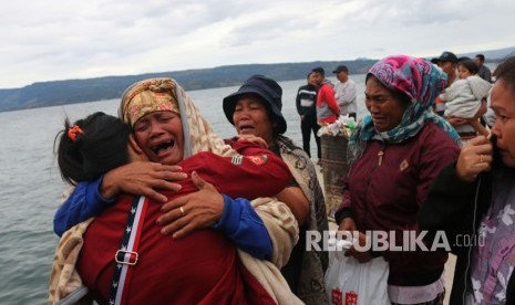 Keluarga penumpang menangis saat menyaksikan proses pencarian penumpang KM Sinar Bangun yang tenggelam di Danau Toba, Simalungun, Sumatra Utara, Selasa (19/6).