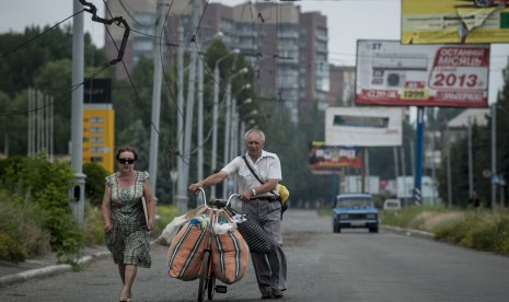 Keluarga Ukraina membawa seluruh miliknya menggunakan sepeda meninggalkan Slovyansk, timur Ukraina, Senin (9/6).