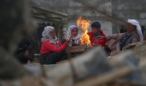 Kelurga Hamouda Abu Amra berkumpul mengelilingi api unggun untuk mengusir dingin tidak jauh dari kediaman mereka yang  di Khan Younis, selatan Jalur Gaza. Bangunan 5 lantai yang dihuni 19 jiwa itu hancur dibombardir serangan udara Israel pada  November tahun lalu.