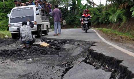 Kendaraan berjalan perlahan saat melintas di jalan raya Banjarnegara-Batur-Wonosobo yang amblas di wilayah Wanayasa, Banjarnegara, Jateng, Sabtu (13/12). Hujan deras beberapa hari terakhir mengakibatkan puluhan titik longsor dan jalan amblas di sepanjang j