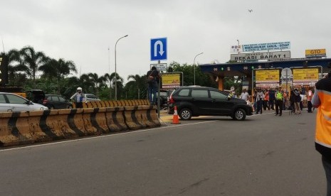 Kendaraan berpelat nomor ganjil memutar arah karena tak boleh memasuki Gerbang Tol Bekasi Barat 1 pada hari pertama penerapan aturan pelat nomor ganjil-genap di Bekasi, Senin (12/3).