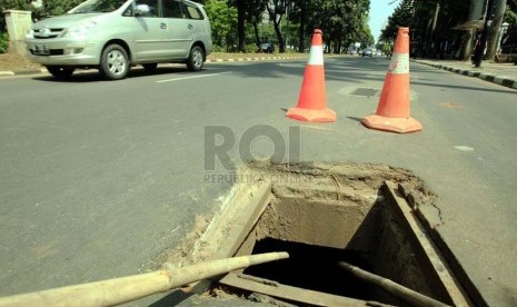 Kendaraan melintas di lubang saluran air di Jalan Sudirman, Jakarta, Selasa (1/7).