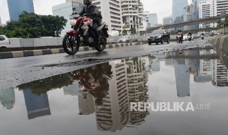 Kendaraan melintas di samping genangan air di Jalan Sudirman, Jakarta Pusat, Senin (1/2).