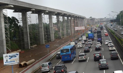 Kendaraan melintas di samping pembangunan  proyek Light Rail Transit (LRT) di Cibubur, Jaktim, Selasa (14/2). 