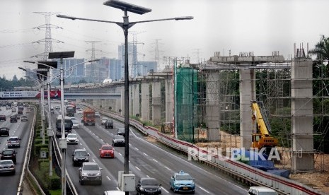 Kendaraan melintas di samping proyek infrastruktur transportasi massal kereta ringan atau Light Rail Transit (LRT) di kawasan Halim, Jakarta, Jumat (30/6). 