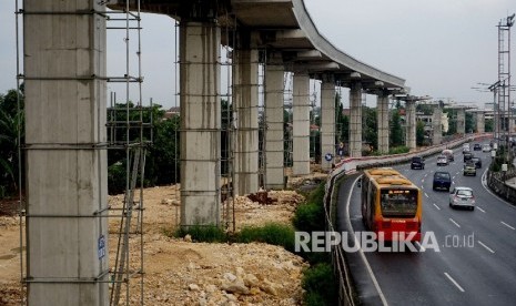 Kendaraan melintas di samping proyek infrastruktur transportasi massal kereta ringan atau Light Rail Transit (LRT) di kawasan Halim, Jakarta. ilustrasi 