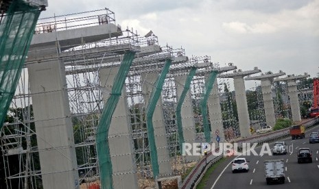 Kendaraan melintas di samping proyek pembangunan tiang penyangga jalur transportasi Light Rail Transit (LRT) rute Cibubur-Cawang di kawasan Halim, Jakarta, Selasa (7/2)