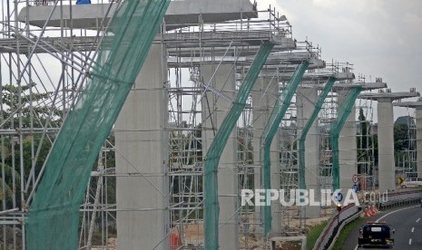 Kendaraan melintas di samping proyek pembangunan tiang penyangga jalur transportasi Light Rail Transit (LRT) rute Cibubur-Cawang di kawasan Halim, Jakarta, Selasa (7/2).