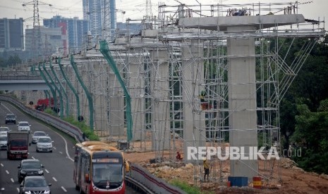 Kendaraan melintas di samping proyek pembangunan tiang penyangga jalur transportasi Light Rail Transit (LRT) rute Cibubur-Cawang di kawasan Halim, Jakarta, Selasa (7/2).