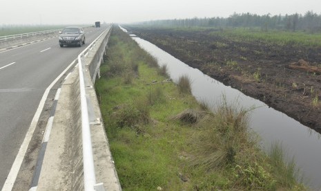 Kendaraan melintas di samping sekat kanal lahan gambut di Jembatan Tumbang Nusa, Kalteng, Kamis (29/10).