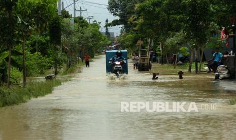 Kendaraan melintasi genangan banjir akibat luapan sungai. 