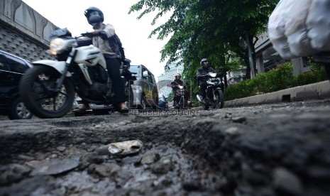 Kendaraan melintasi jalan yang rusak di kawasan Karet, Jakarta Pusat, kamis (12/2).